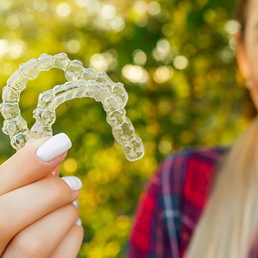 Teenage girl holding two Invisalign aligners