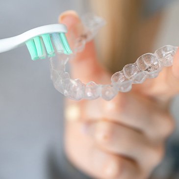 Closeup of patient cleaning clear aligner