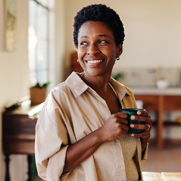 Woman smiling while drinking coffee at home