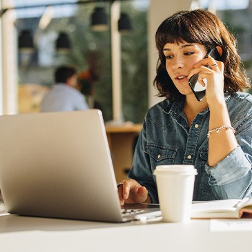 Woman talking on phone while working on laptop