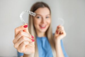 Teenaged girl holding Invisalign in foreground.