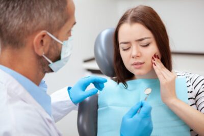 Dentist tending to patient in pain in dentist's chair.